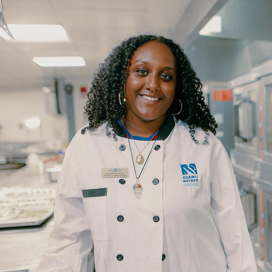 Eden wearing cooking uniform stands in Campus Center kitchen.